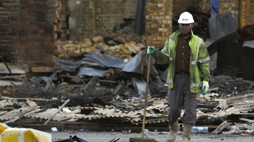 Un trabajador limpia los escombros de lo que era una tienda de muebles al sur de Londres