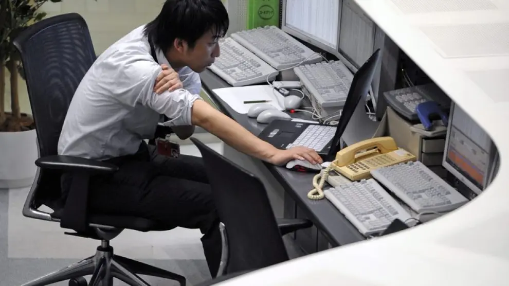 Un corredor de bolsa observa los datos bursátiles en un ordenador en la bolsa de Tokio