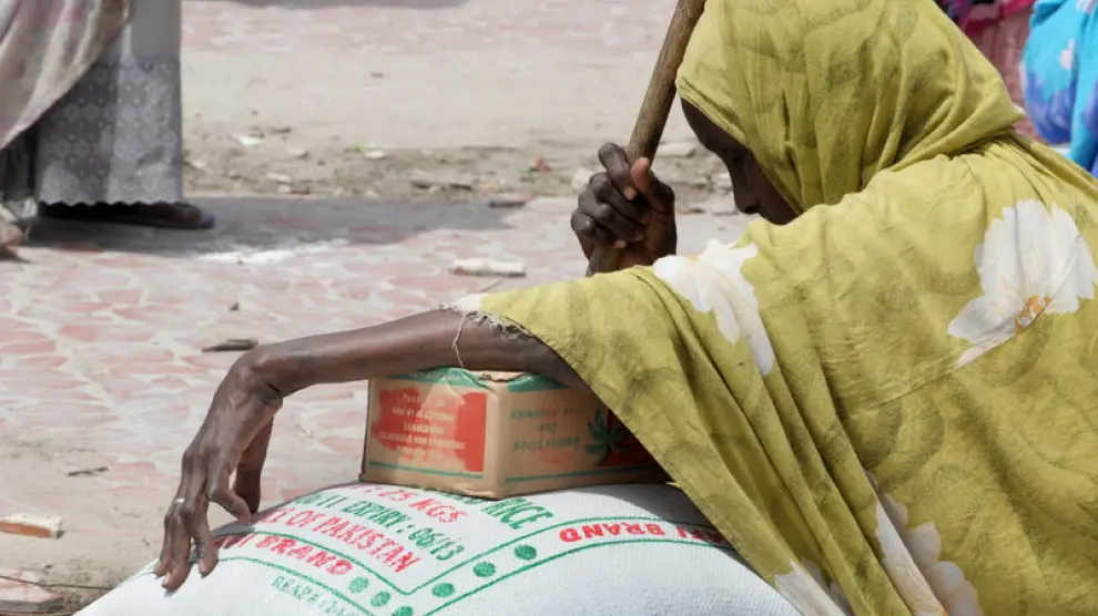 Una anciana refugiada apollada encima de un saco de arroz