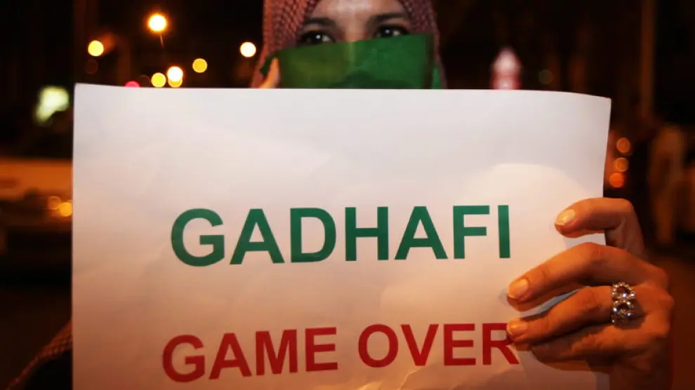 Opositora a Gadafi muestra un cartel en su contra