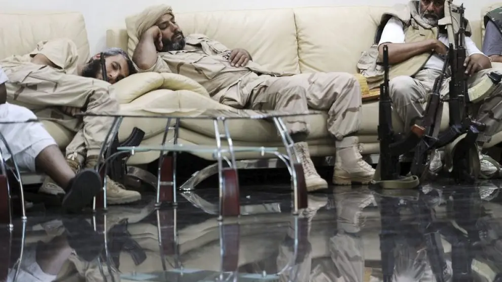 Unos soldados rebeldes libios descansan en la antigua sede del Ministerio de Petróleo en Trípoli