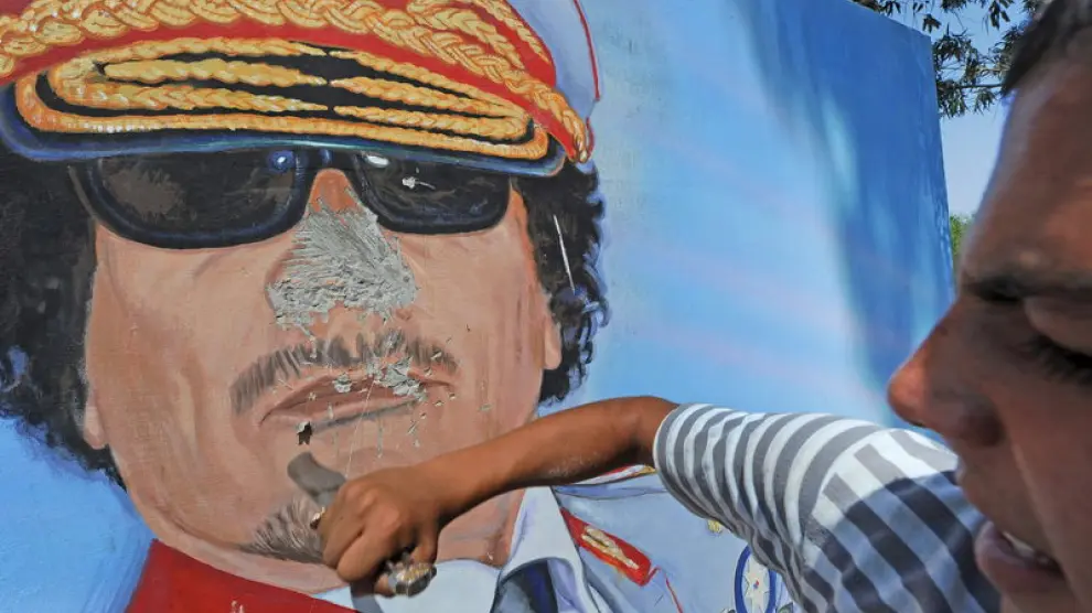 Un hombre destroza un mural de Gadafi