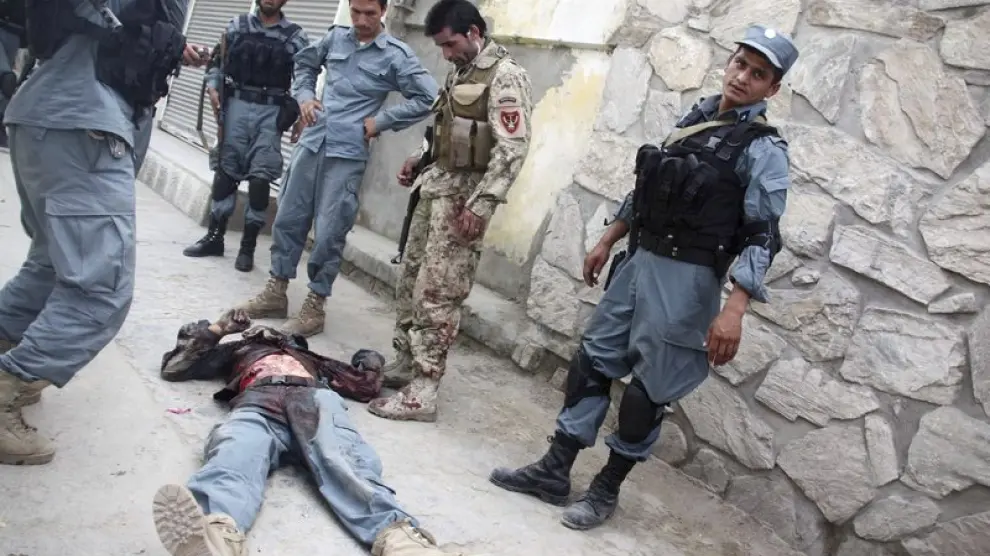 Policías afganos permanecen junto al cuerpo de un compañero muerto en el tiroteo de Kabul