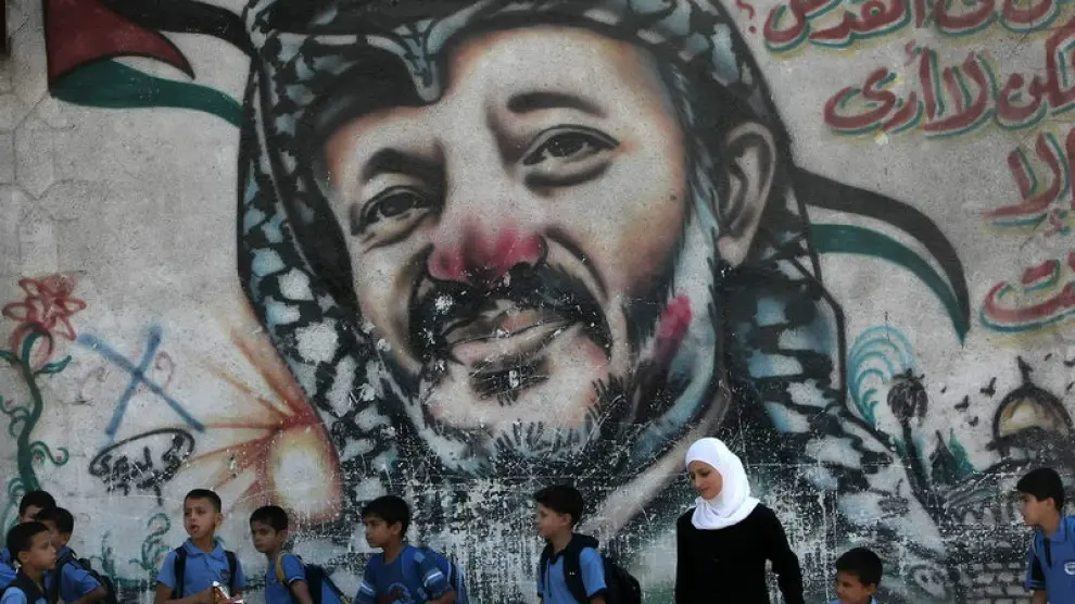 Escolares ante un mural con la foto de Arafat, en Gaza