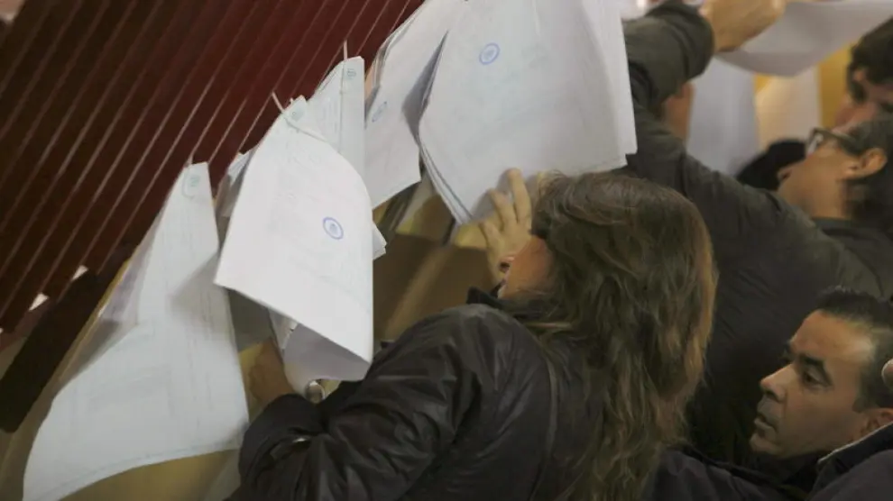 Unos ciudadadanos consultan las listas en un colegio electoral de Madrid