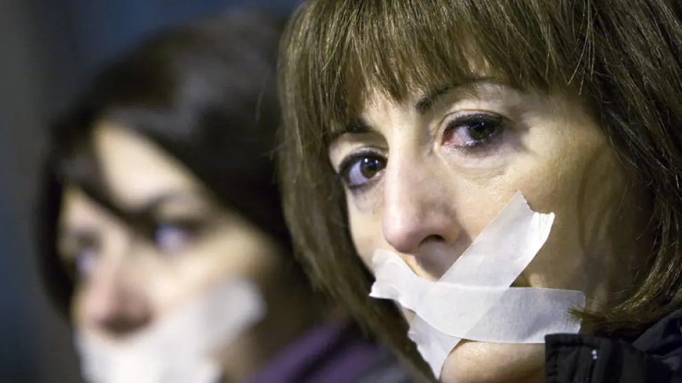 Dos mujeres se tapan la boca durante una manifestación contra la violencia de género en Zaragoza