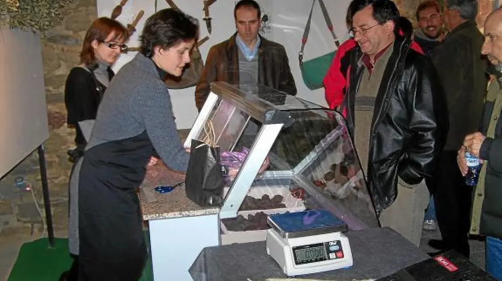 Varios turistas (el pasado invierno) se interesan por la trufa que oferta el mercado de Graus.