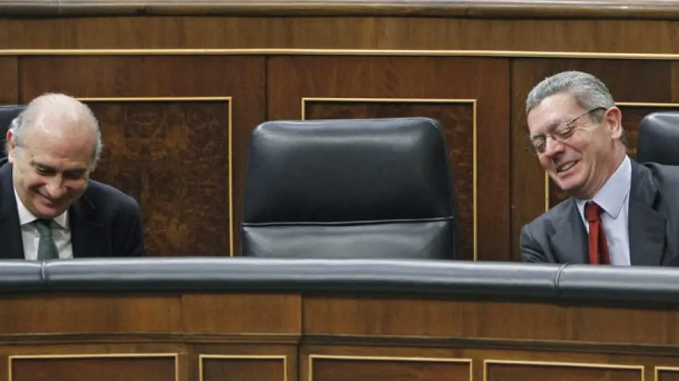 El ministro del Interior (i) y el de Justicia (d) sonríen en sus escaños durante el Pleno.