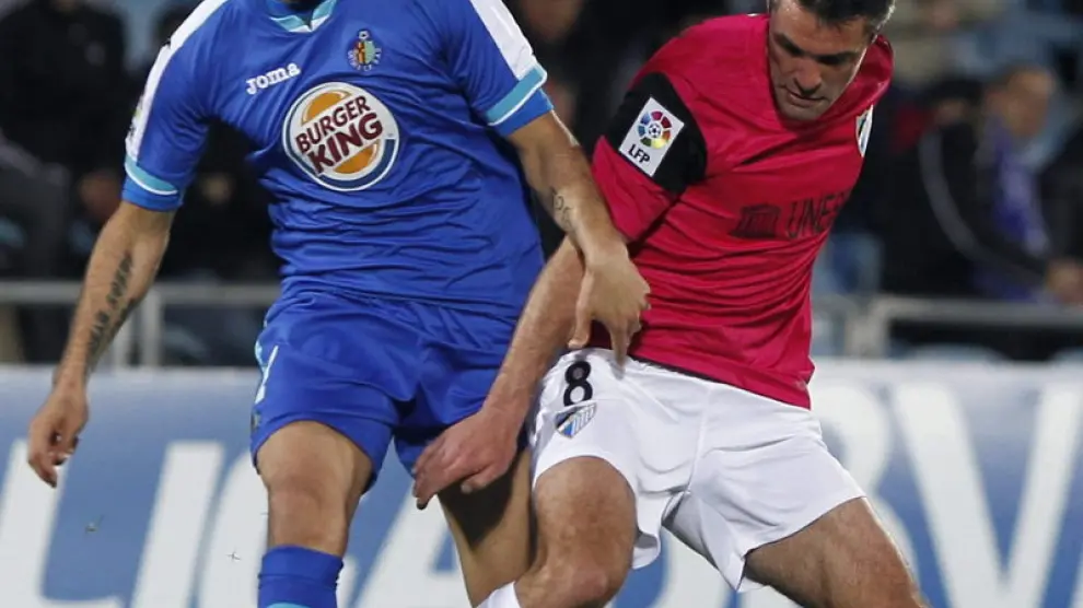 El delantero del Getafe, Nicolás Fedor, intenta robar el balón al centrocampista del Málaga, Jérémy Toulalan.
