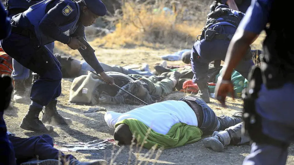 Unos policías inspeccionan los cuerpos sin vida de unos mineros