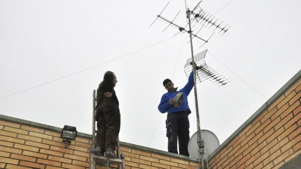 Unos técnicos ajustan la antena de televisión de una vivienda