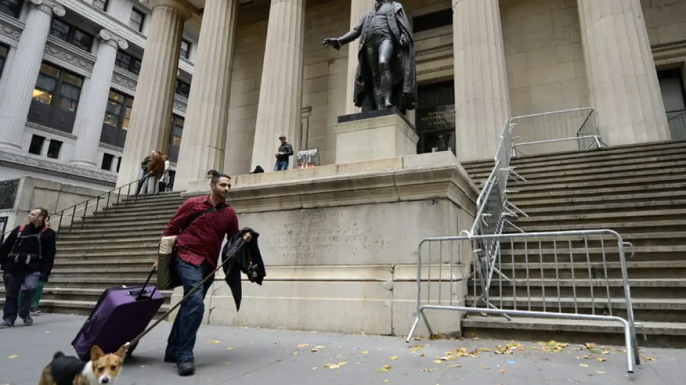 Un neoyorquino pasa con su equipaje junto a Wall Street.