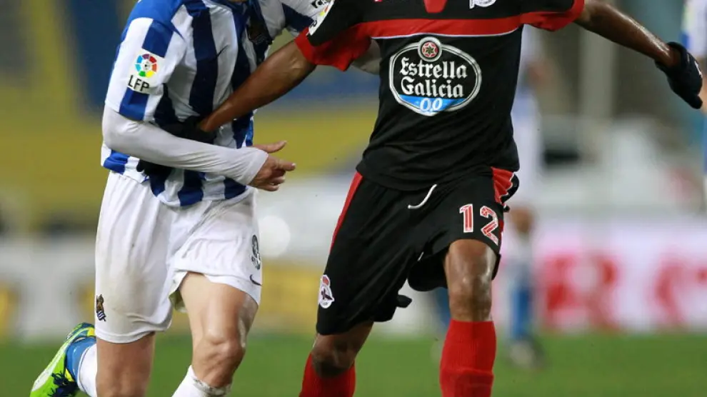 El delantero de la Real Sociedad Imanol Agirretxe (i), intenta alcanzar un balón controlado por el brasileño del R.C. Deportivo, Paulo Assunção (d)