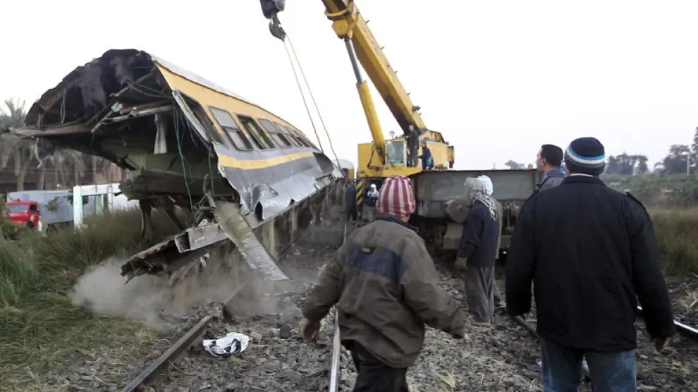 Miembros de los equipos de rescate levantan un vagón de tren tras un accidente en Guiza.