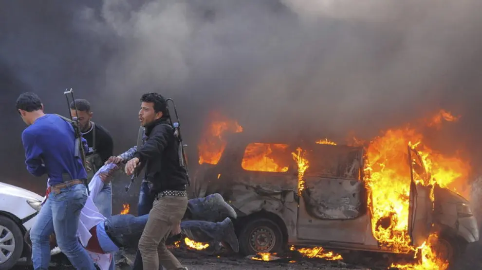 Tres rebeldes sirios llevan en volandas a un herido en el atentado en Damasco.