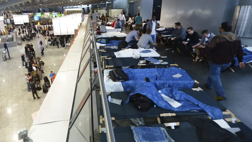 Varios pasajeros esperan en camas plegables en la Terminal 1.