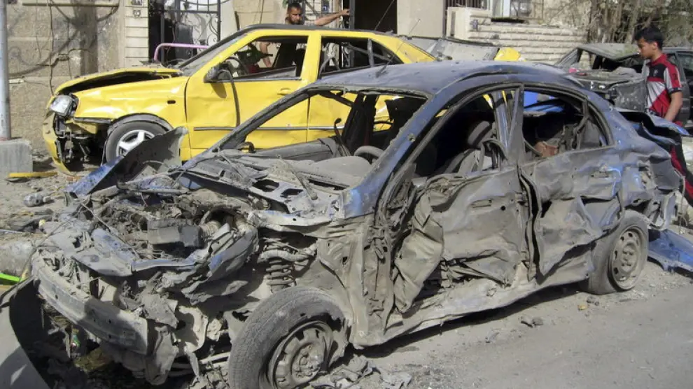 Dos hombres inspeccionan los coches dañados tras la explosión en Bagdad