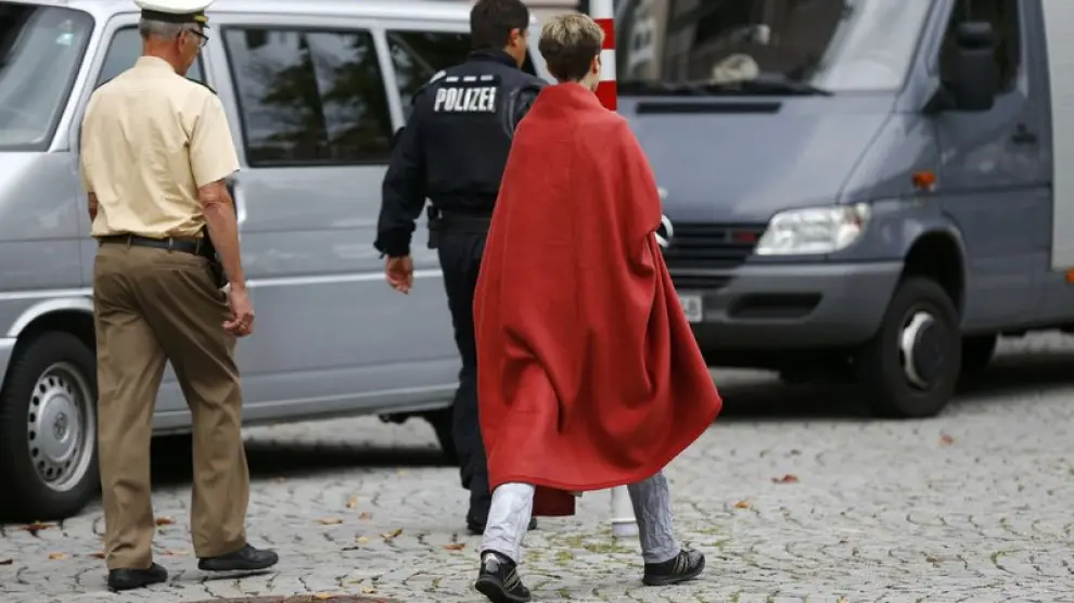 Una mujer sale del escenario de los hechos acompañada de un policía.