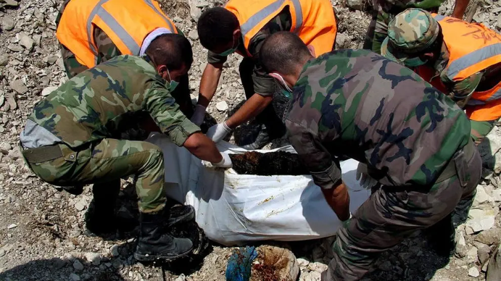 Miembros de la defensa civil siria recogen un cuerpo