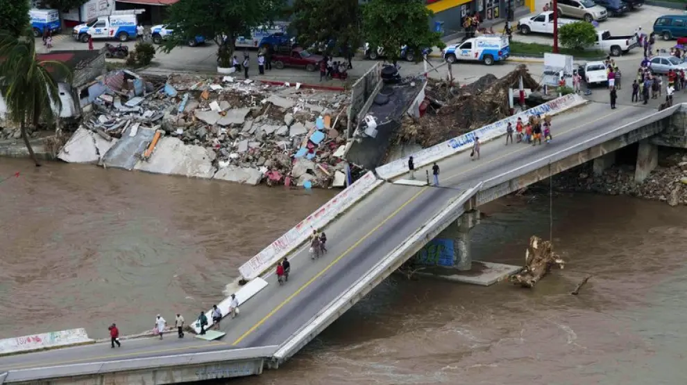 La gente camina por un puente roto en Acapulco