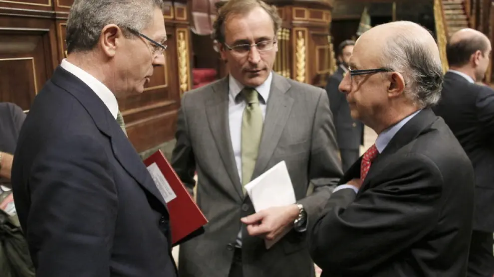 Los ministros, de Justicia, Alberto Ruiz-Gallardón (i), y de Hacienda, Cristóbal Montoro (d), y el portavoz parlamentario del PP, Alfonso Alonso
