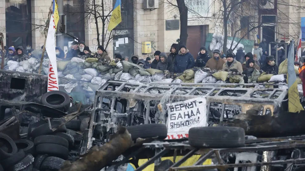 Decenas de manifestantes permanecen de pie frente a una barricada en Kiev.