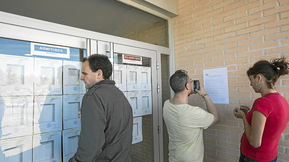Unos padres miran las listas de alumnos admitidos en el colegio de Montecanal.