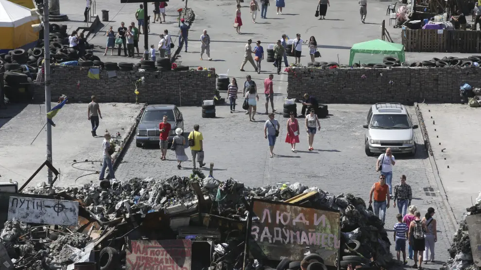 Varias personas caminan junto a las barricadas colocadas en Kiev, otras de las zonas de conflicto