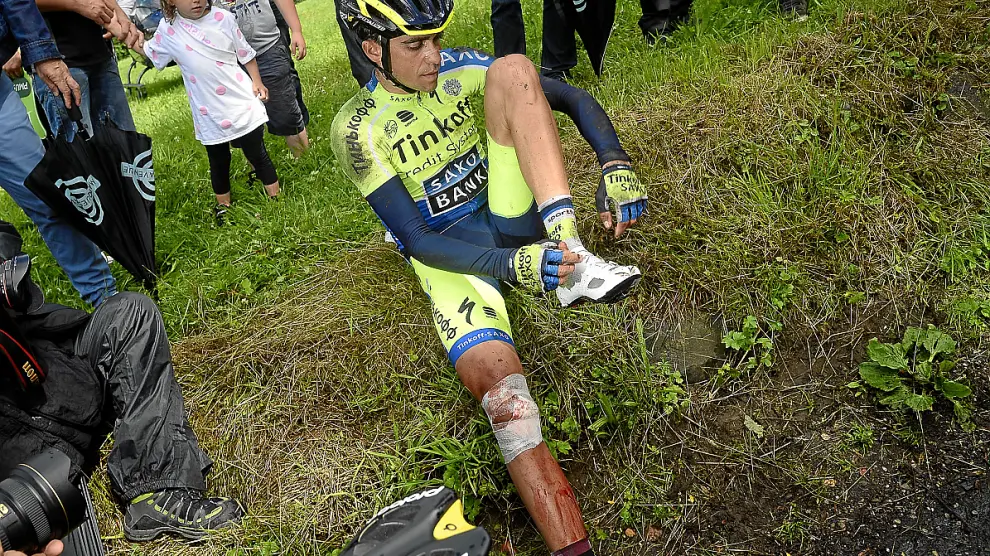 Contador, con la rodilla derecha ensangrentada, se calza las zapatillas tras sufrir la caída.