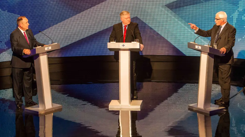 Salmond (izquierda) escucha a Darling (derecha) ante la mirada del moderador del debate