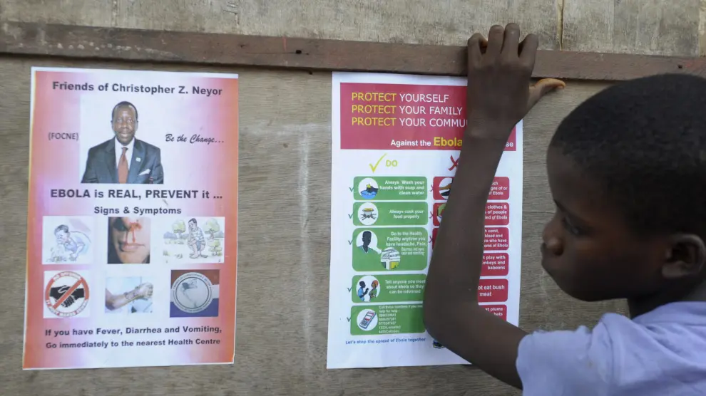 Un niño observa unos carteles con instrucciones de prevención del virus del ébola en Monrovia