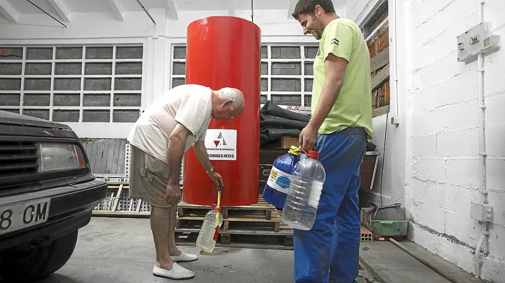 Fidel Botaya y su nieto, Sergi Lombarte, cogen agua de una cuba de los bomberos en Santa Eulalia.