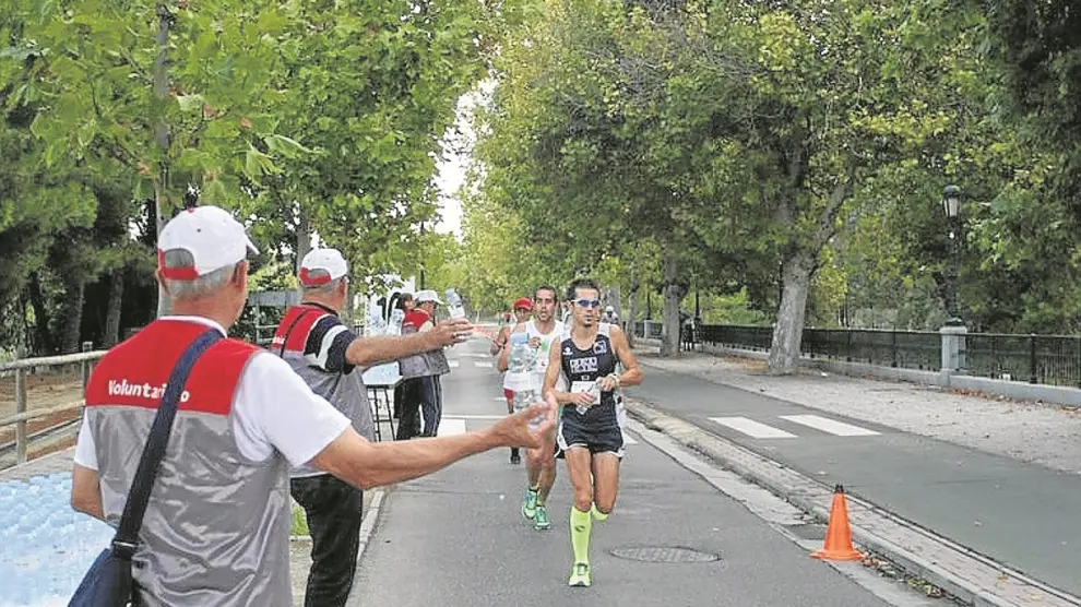 Un grupo de corredores del Maratón pasa por un punto de avituallamiento en la pasada edición.