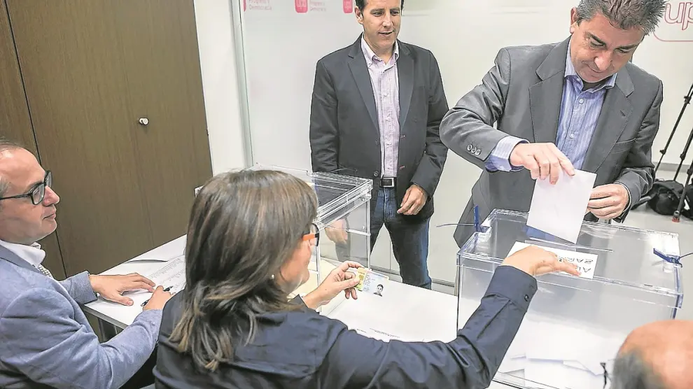 El candidato municipal, Javier Puy, vota en la sede, mientras espera el autonómico, Carlos Aparicio.
