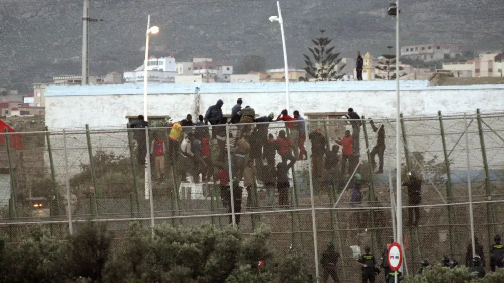 Inmigrantes encaramados en la valla de Melilla este viernes