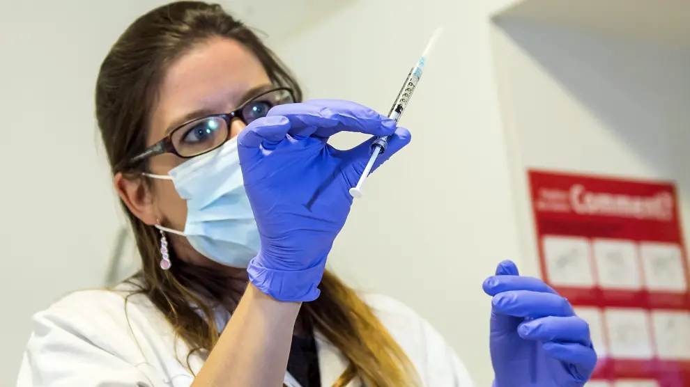 Una enfermera sostiene una dosis de la vacuna experimental contra el ébola antes de inyectásela a un voluntario de una ONG