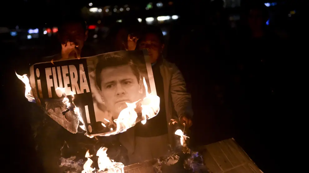 Dos manifestantes queman una imagen del presidente Peña Nieto