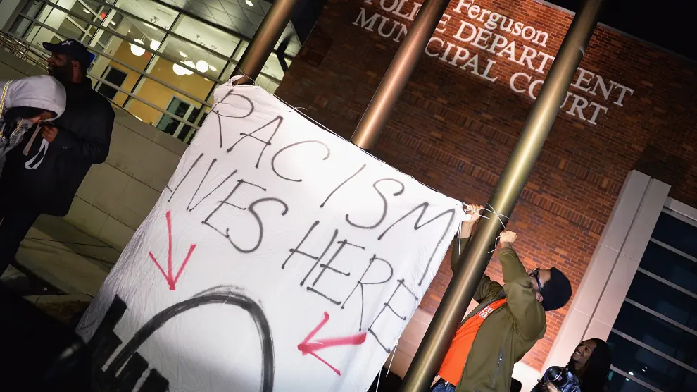 "El racismo vive aquí". Un joven despliega una pancarta durante las protestas frente al Departamento de Policía de Ferguson