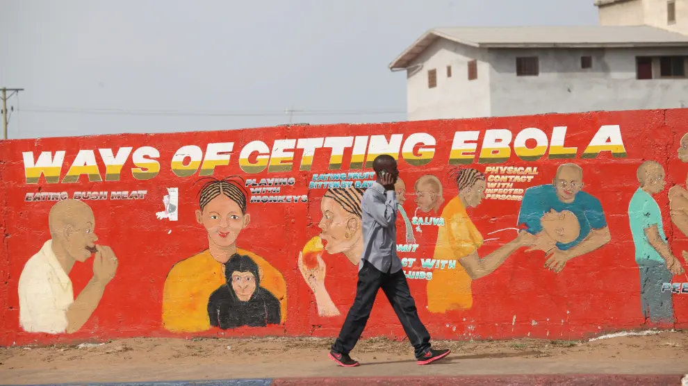 Un ciudadano de Liberia pasea por delante de un mural divulgativo pintado para concienciar sobre la epidemia de ébola.