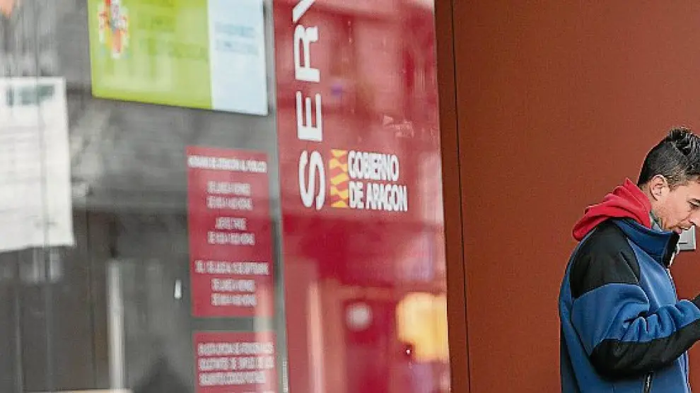 Un ciudadano consulta su móvil junto a una oficina de empleo del Inaem, en Aragón.