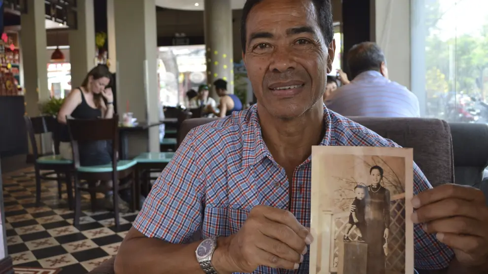 René Fairn, de 66 años, de padre militar francés y madre vietnamita, muestra una fotografía suya junto a su madre en Vietnam.