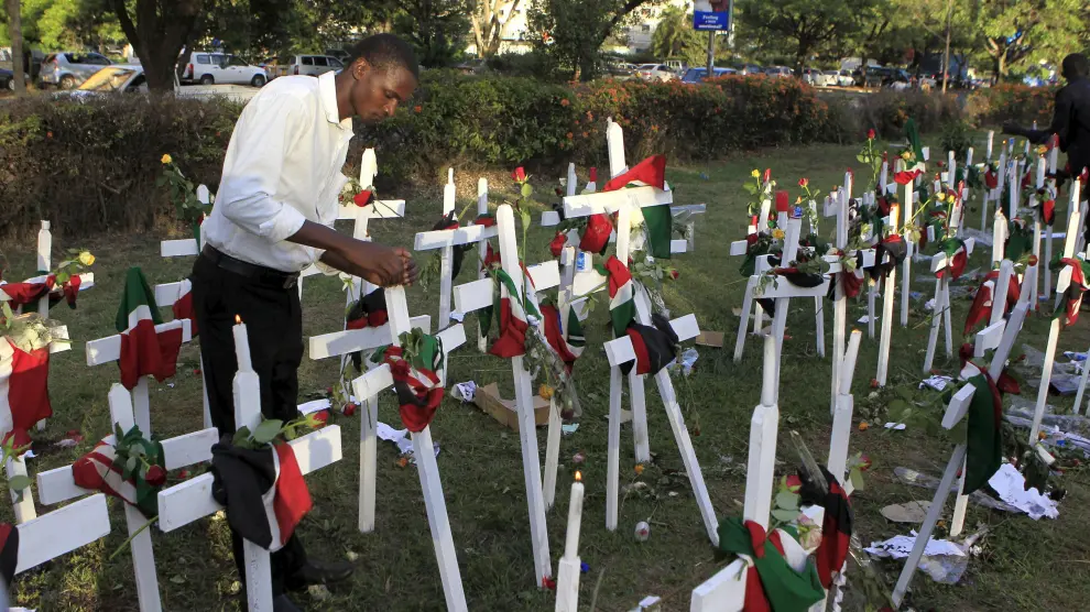 Un hombre enciende una vela cerca de cruces de madera en la esquina de Libertad en Nairobi.