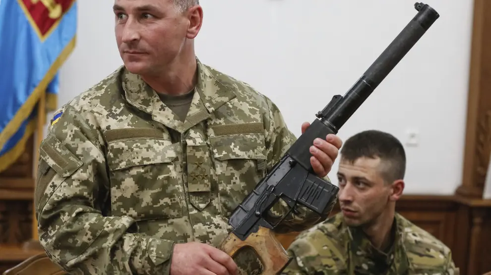Un soldado muestra un arma que pertenece a uno de los oficiales rusos detenidos este lunes en Ucrania.