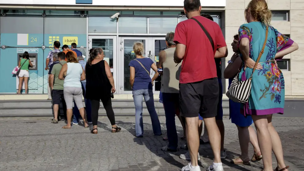 Varias personas haciendo cola para sacar dinero en un cajero en Grecia.