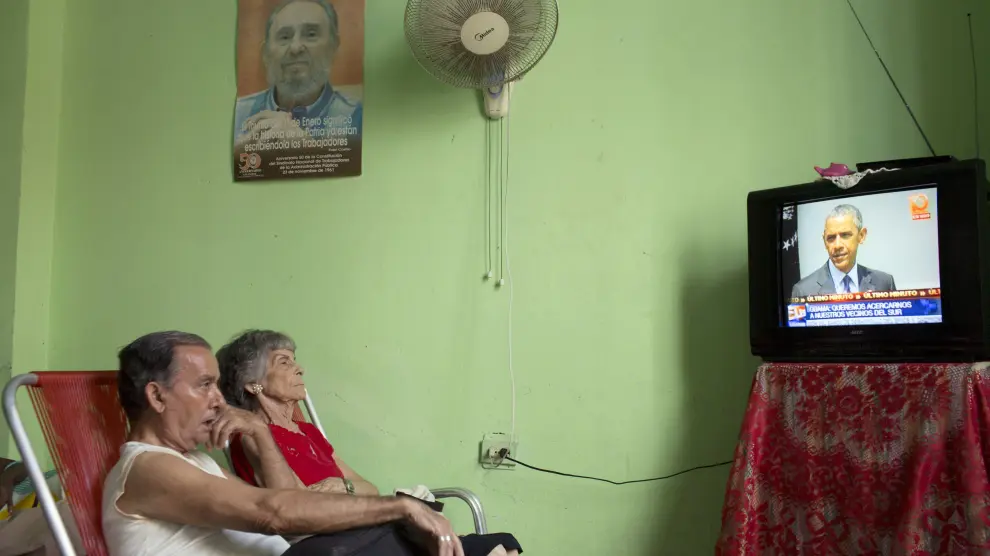 Unos cubanos escuchan en su casa a Obama por televisión.