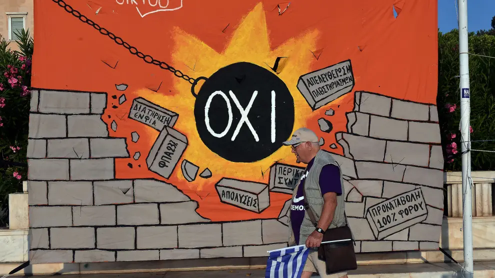 Un hombre pasa frente a una pared con un 'grafitti' anti austeridad