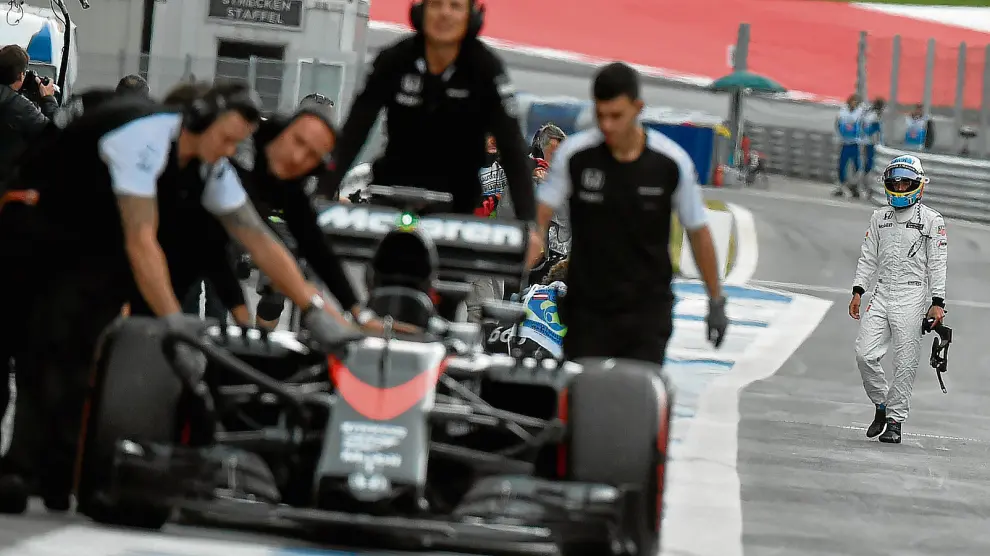 Fernando Alonso, al fondo, observa cómo retiran su monoplaza, ayer en el circuito Red Bull Ring.