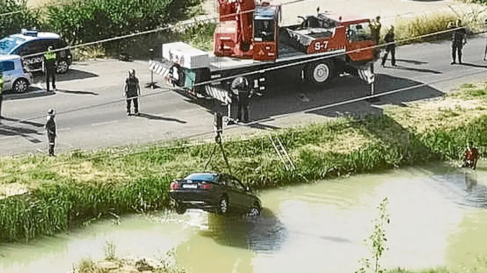 Momento en el que la grúa de los bomberos extrae el coche de las aguas del Canal.