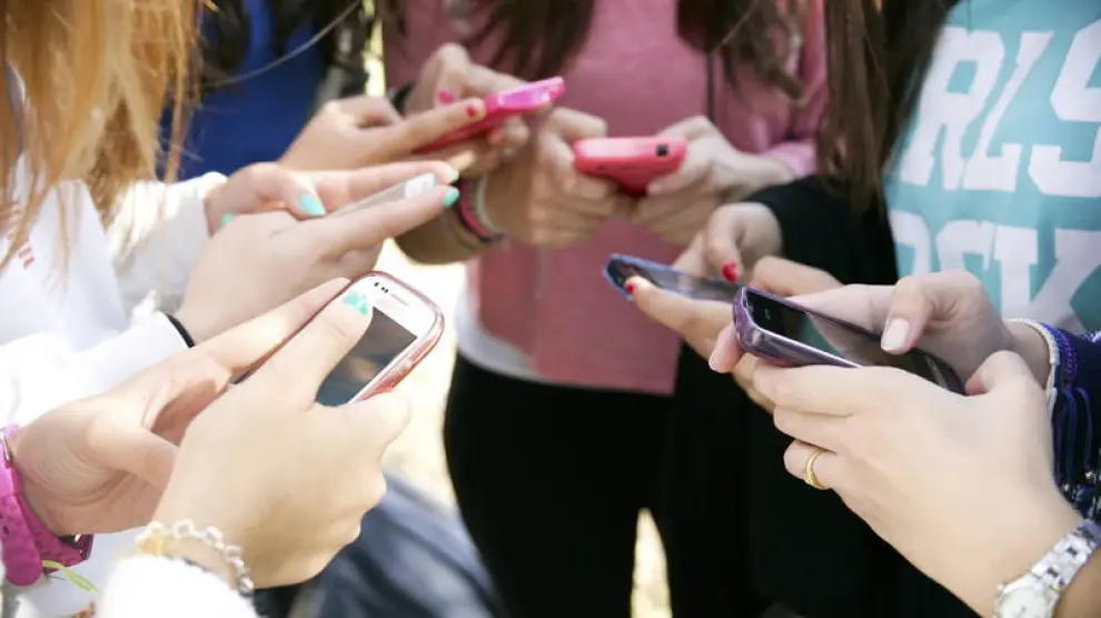 Un grupo de adolescentes usan sus teléfonos en un instituto.