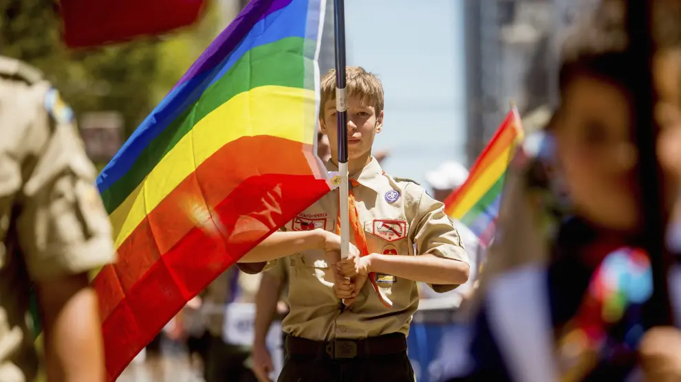 Un boy scout desfilando con la bandera homosexual.